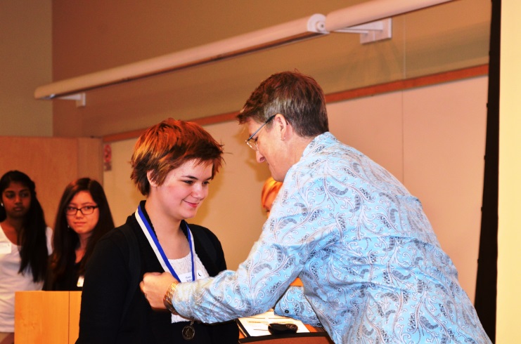 Assistant Director Jan Warren awards a medal to an Iowa Scholastic student at the April 2015 Awards Ceremony